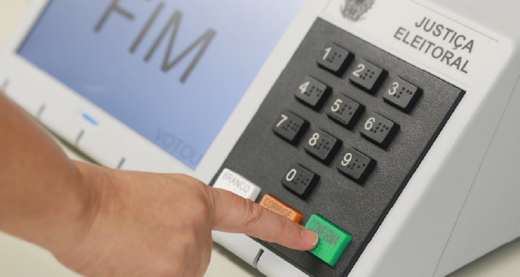 Fotografia de pessoa digitando em urna eletrônica
