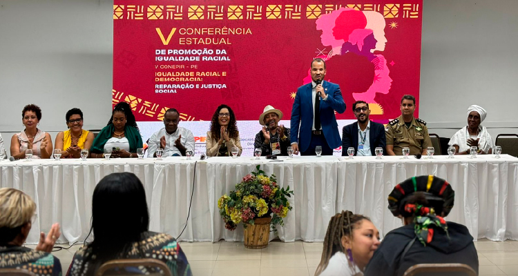 Fotografia de participantes do evento falando da mesa principal
