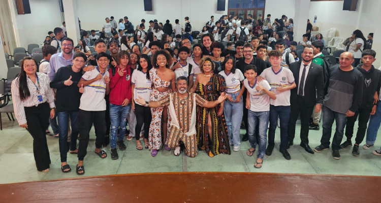 Um grupo diversificado de adultos e jovens posa para uma foto em um auditório