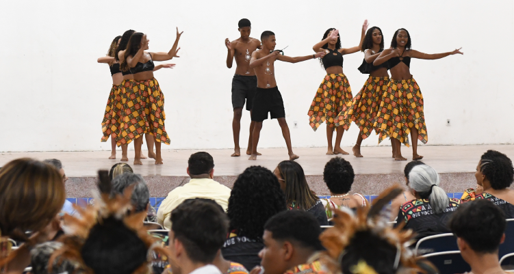 Fotografia e estudantes dançando no palco diante do público