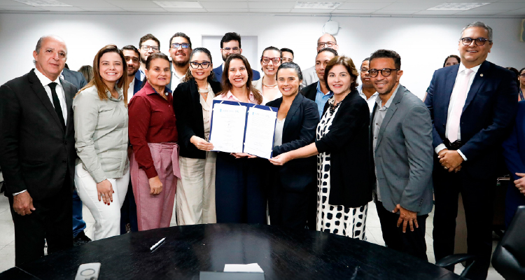 Fotografia de participantes do evento segurando documento assinado