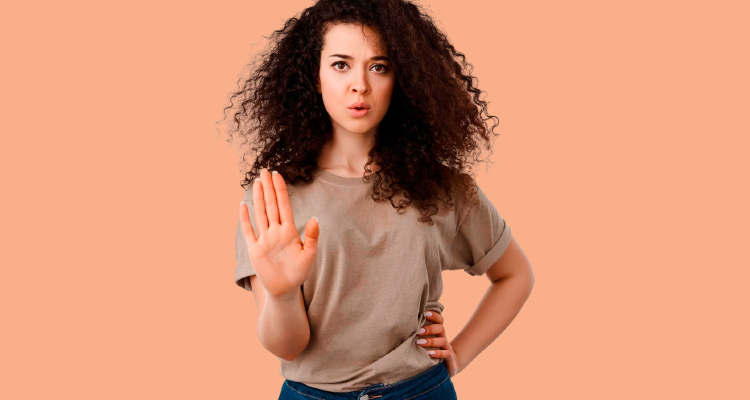 Fotografia de mulher de pé fazendo sinal de pare com a mão