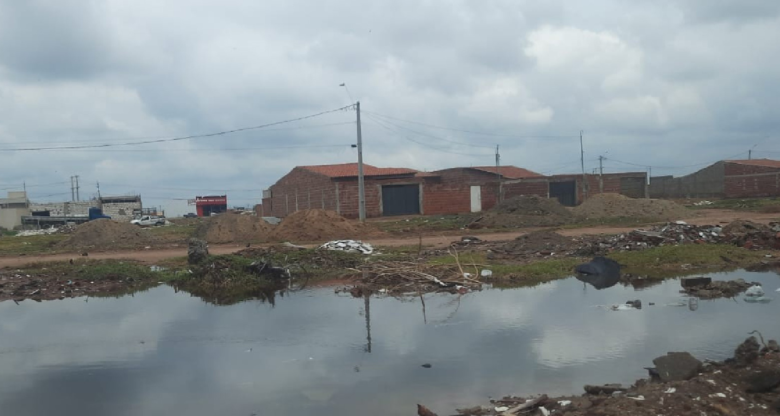 Fotografia de casas no loteamento com água estagnada na frente