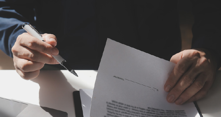 Imagem de pessoa com caneta na mão escrevendo em papéis